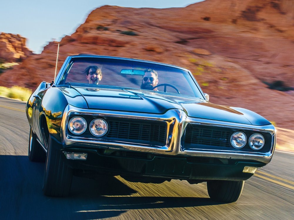 couple driving together in cool vintage car through desert